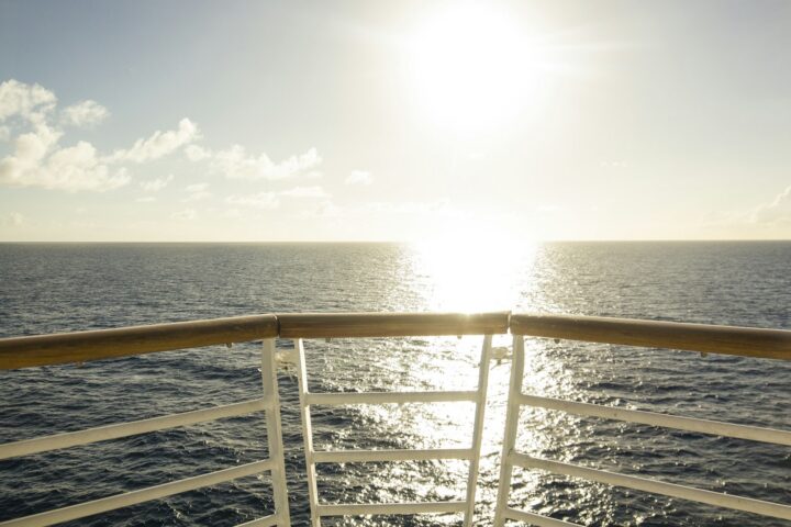 Sun over the sea seen from a ship railing