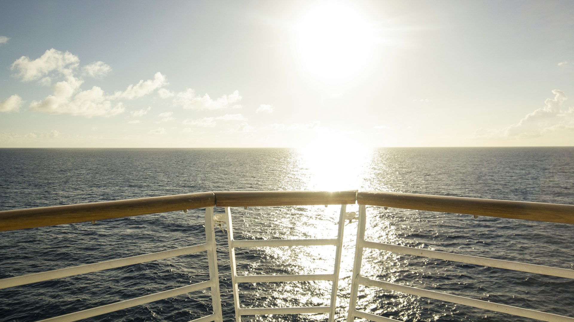 Sun over the sea seen from a ship railing