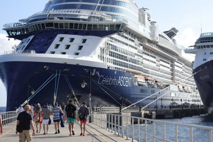 Passengers walking along a pier beside Celebrity Ascent