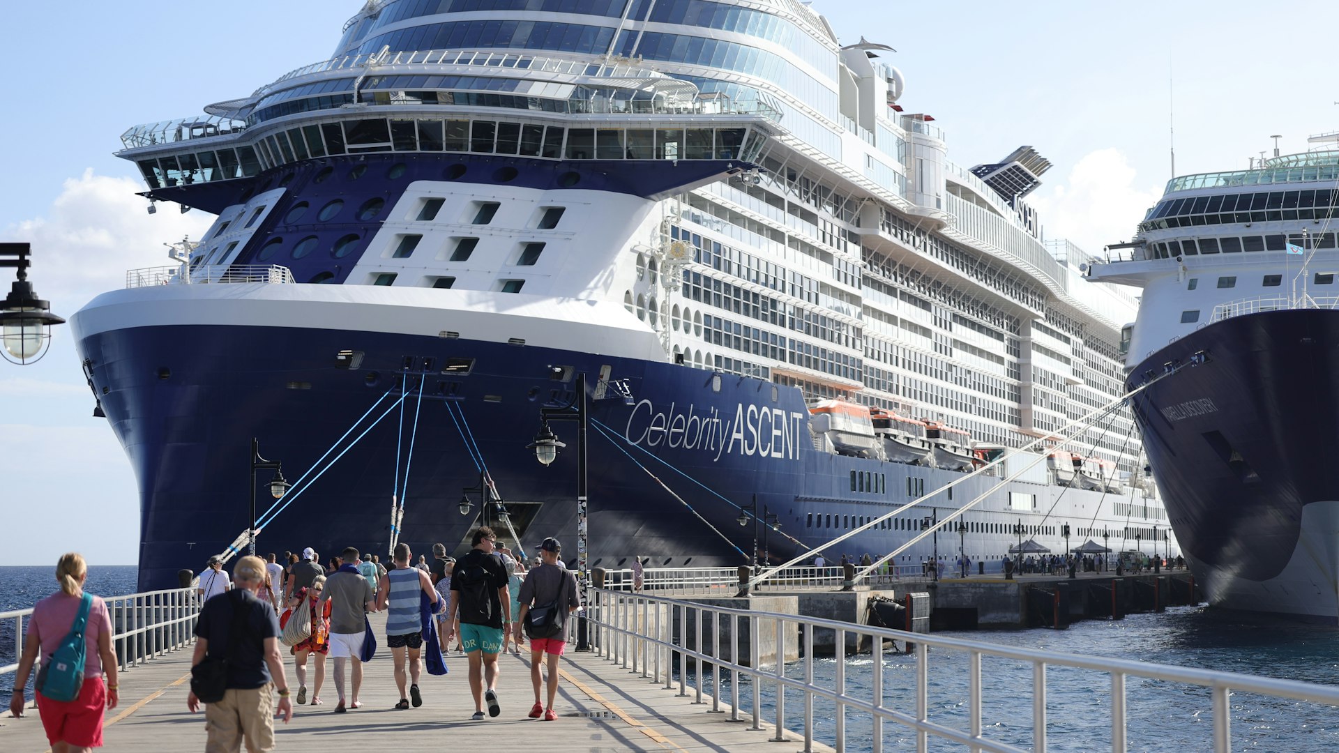 Passengers walking along a pier beside Celebrity Ascent