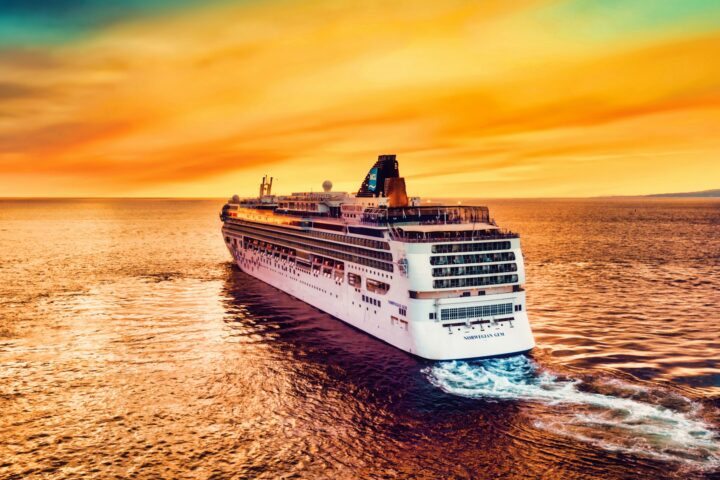 Norwegian Cruise Line ship sailing toward a golden sunset