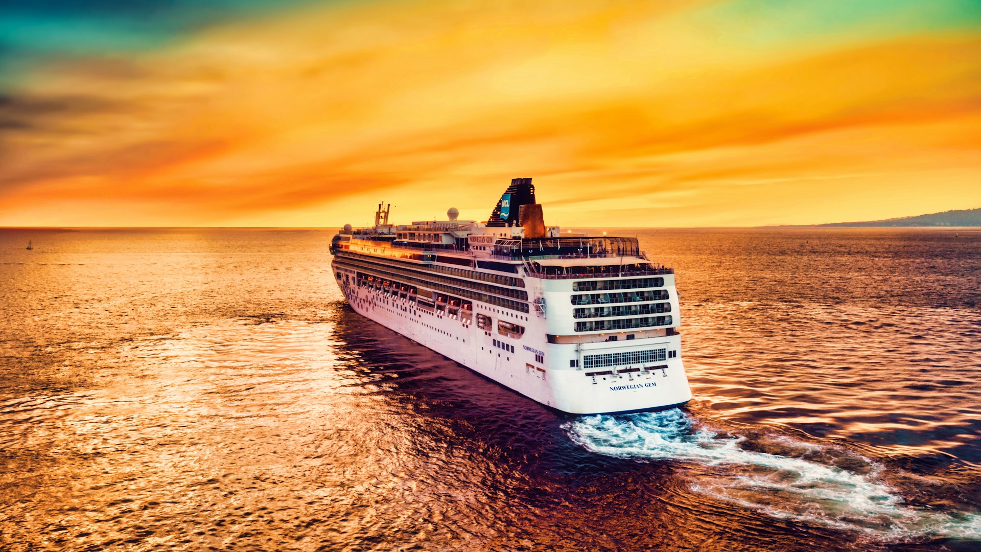 Norwegian Cruise Line ship sailing toward a golden sunset