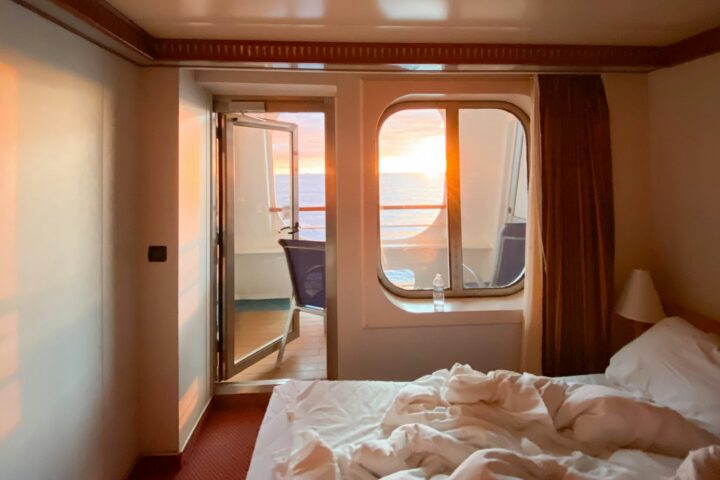 Ship cabin with a balcony door and sunset light through the window
