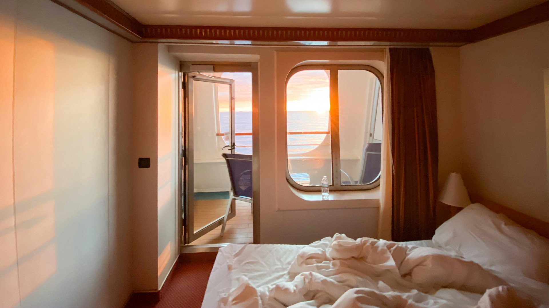 Ship cabin with a balcony door and sunset light through the window
