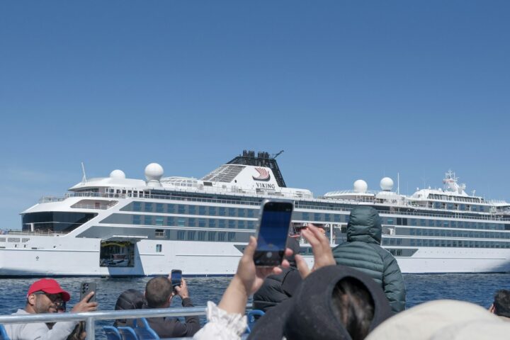 Tour boat passengers photographing a white cruise ship