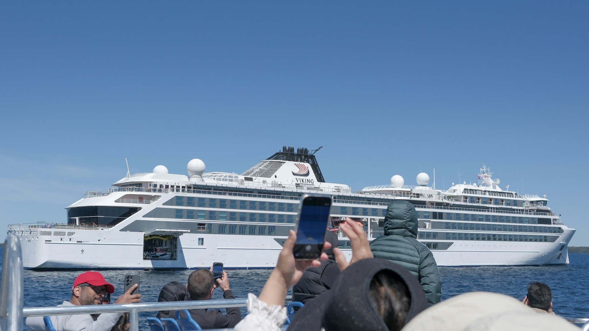 Tour boat passengers photographing a white cruise ship