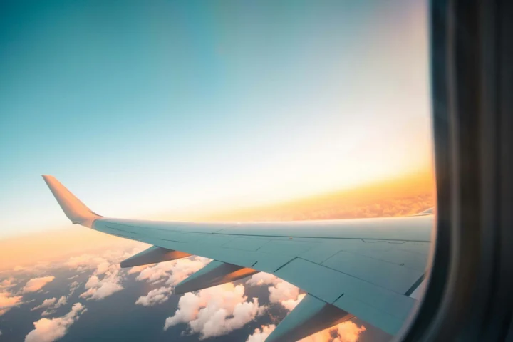 Airplane wing seen through the cabin window at sunset