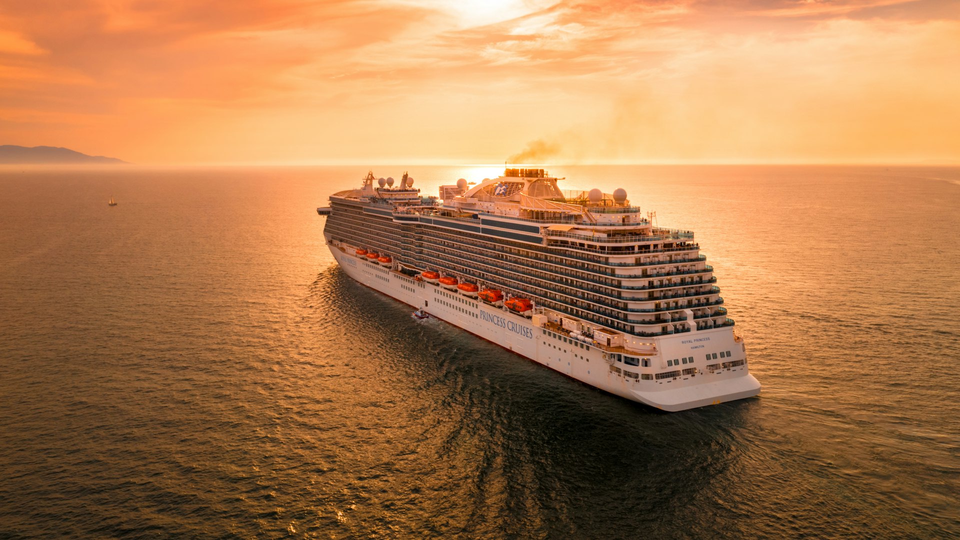 Cruise ship sailing across a calm sea at sunset