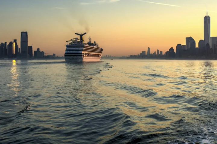 Cruise ship sailing past the Manhattan and Jersey City skylines at sunset