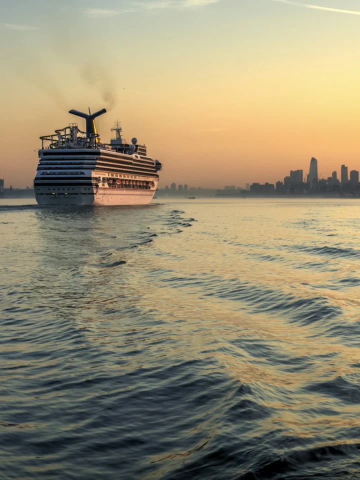 Cruise ship sailing past the Manhattan and Jersey City skylines at sunset