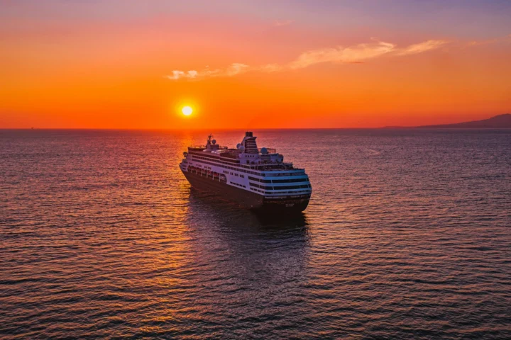 Cruise ship sailing toward the sunset on open sea