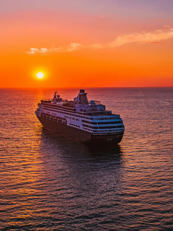 Cruise ship sailing toward the sunset on open sea